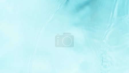 Foto de Congelar el movimiento de la superficie de agua salpicando sobre fondo azul claro - Imagen libre de derechos