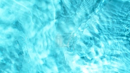 Téléchargez les photos : Geler le mouvement des éclaboussures de surface de l'eau sur fond bleu clair - en image libre de droit