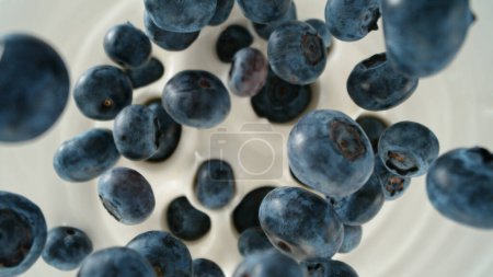 Photo for Fresh blueberries falling into yoghurt cream, top down view - Royalty Free Image