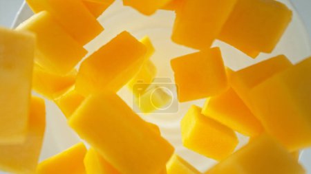 Photo for Fresh mango pieces falling into yoghurt cream, top down view - Royalty Free Image