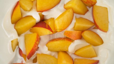 Téléchargez les photos : Nectarines fraîches morceaux tombant dans la crème de yaourt, vue du haut vers le bas - en image libre de droit