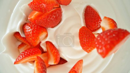 Photo for Fresh strawberries falling into yoghurt cream, top down view - Royalty Free Image