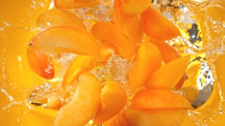 Téléchargez les photos : Fresh apricots pieces falling into water, top down view - en image libre de droit