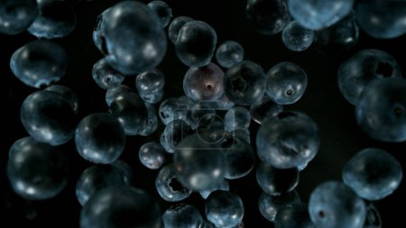Photo for Fresh pieces of blueberries falling into water, top down view, black background - Royalty Free Image