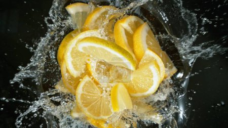 Téléchargez les photos : Morceaux de citron frais tombant dans l'eau, vue du haut vers le bas - en image libre de droit