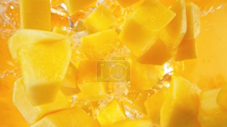 Photo for Fresh mango pieces falling into water, top down view - Royalty Free Image