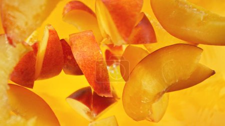 Fresh nectarine pieces falling into water, top down view