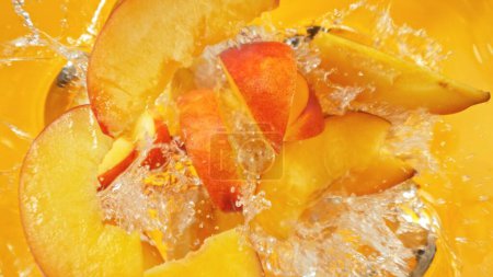 Photo for Fresh nectarine pieces falling into water, top down view - Royalty Free Image