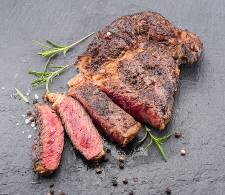 Téléchargez les photos : Steak de côtelette grillé moyen et rare sur plaque de pierre grise. - en image libre de droit