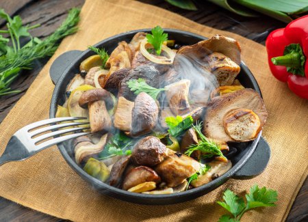 Photo for Just cooked steaming porcini mushrooms in the frying pan on the wooden table. Top view. - Royalty Free Image