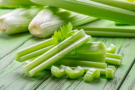 Photo for Pile of celery ribs on green wooden table. Healthy food background. - Royalty Free Image