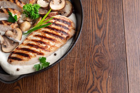 Téléchargez les photos : Filet de poulet rôti et champignons avec des herbes dans la poêle sur la table en bois close-up. - en image libre de droit
