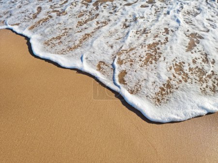 Photo for Ocean foam covering beautiful sandy beach. Top view. - Royalty Free Image