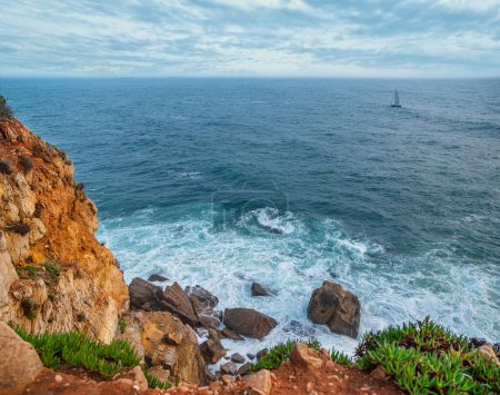 Foto de Hermoso cielo nublado y olas espumosas acercándose a la costa rocosa del océano Atlántico. Hermosa naturaleza de fondo de Portugal. - Imagen libre de derechos