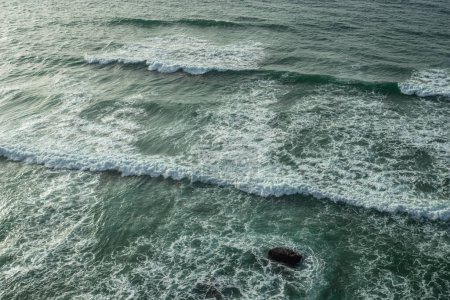 Téléchargez les photos : Des vagues mousseuses s'approchent du rivage rocheux. Vue du dessus. - en image libre de droit