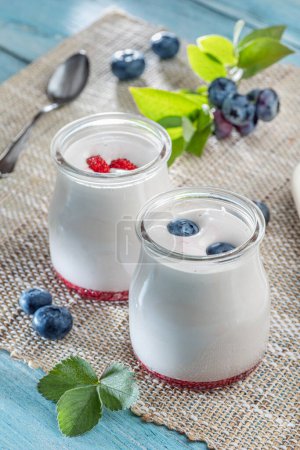 Photo for Two glass containers with plain yoghurt and berries on the table. Light summer mood. - Royalty Free Image