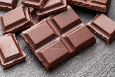 Téléchargez les photos : Des morceaux de chocolat au lait sur fond gris. Les aliments sucrés sont faits de cacao et de sucre. - en image libre de droit