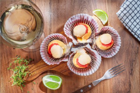 Foto de Fresh opened scallop with scallop roe or coral with glass of white wine. Top view. - Imagen libre de derechos