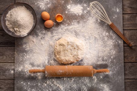 Photo for Ready to be baked dough. Top view of board, rolling pin and flour and dough. - Royalty Free Image