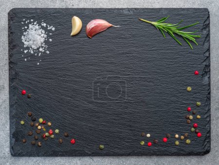 Téléchargez les photos : Natural stone black slate serving plate with seasonings and spices arranged as a frame. Flat lay. - en image libre de droit