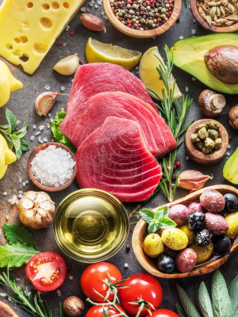 Téléchargez les photos : Raw tuna steaks with spices and vegetables on the graphite board. Mediterranean kitchen. Top view. - en image libre de droit