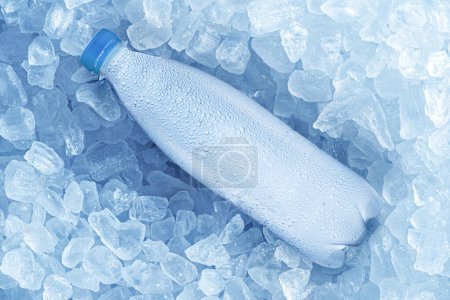 Cold bottle of water over ice cubes. Food and drink background.