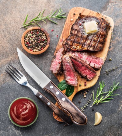 Téléchargez les photos : Steak Ribeye moyen et rare avec des herbes et un morceau de beurre sur le plateau en bois. Vue du dessus
; - en image libre de droit
