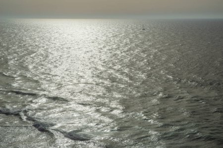 Téléchargez les photos : Glittering surface de l'eau de l'océan et petit bateau à une certaine distance. - en image libre de droit