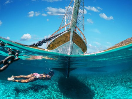 Foto de Chica buzo está haciendo snorkel en una hermosa playa de mar. La mitad inferior de la imagen está ocupada por el fondo del mar, en la parte superior - la costa con un yate y un hermoso cielo. - Imagen libre de derechos