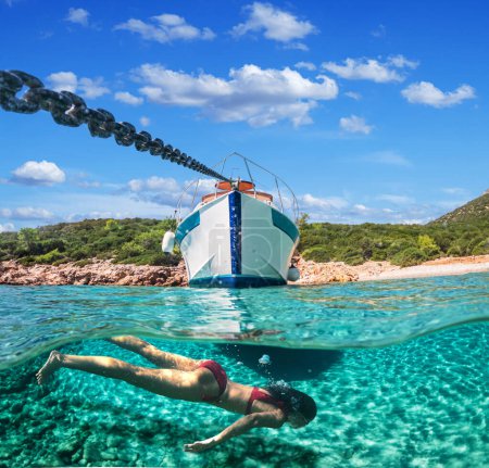 Téléchargez les photos : Femme plongeuse est plongée avec tuba sur une belle plage de la mer. La moitié inférieure de l'image est occupée par le fond marin, sur le dessus - la côte avec un yacht et un beau ciel. - en image libre de droit