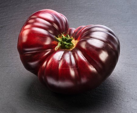 Foto de Tomate maduro negro o púrpura sobre fondo de pizarra gris. - Imagen libre de derechos