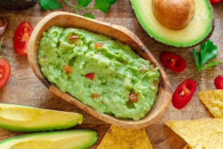 Photo for Guacamole, guacamole ingredients and chips on wooden background.  Flat lay. - Royalty Free Image