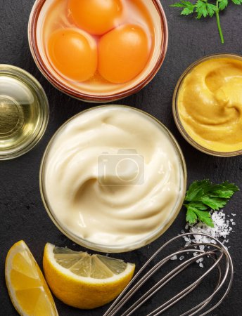Photo for Homemade mayonnaise and mayo ingredients on black stone slate serving plate. Flat lay. - Royalty Free Image