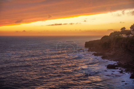 Téléchargez les photos : Coucher de soleil coloré rouge et ciel dramatique vif sur la rive rocheuse de l'océan Atlantique. - en image libre de droit