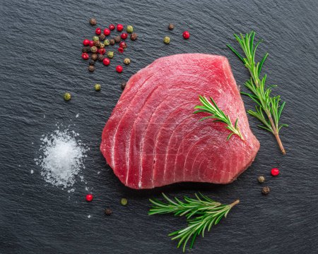 Foto de Raw tuna fish steak on natural stone black slate serving plate. Top view. - Imagen libre de derechos
