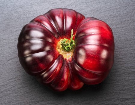 Foto de Tomate maduro negro o púrpura sobre fondo de pizarra gris. Vista superior. - Imagen libre de derechos