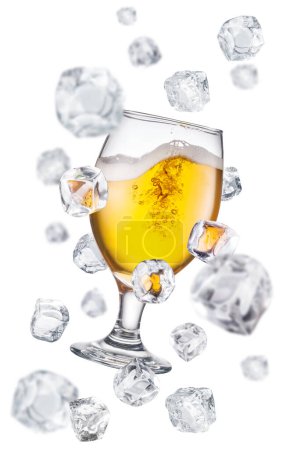 Foto de Cerveza rodeada de cubos de hielo voladores. Imagen conceptual del enfriamiento de vidrio de cerveza. - Imagen libre de derechos