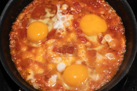 Photo for Shakshouka cooking in iron pan top view. - Royalty Free Image