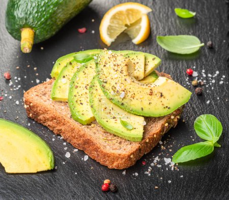 Photo for Avocado toast - bread with avocado slices on natural slate serving board. Top view. - Royalty Free Image