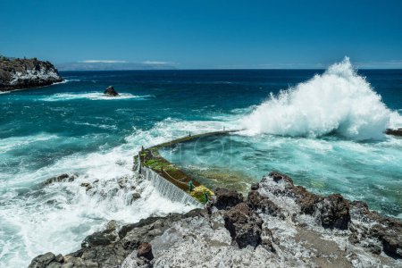 Foto de Costa rocosa y gran ola rompiendo en piscina natural de la isla de Tenerife. - Imagen libre de derechos