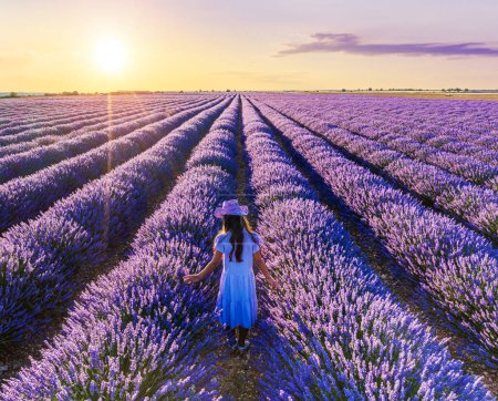 Photo for Young girl walking  in the lavender field and stunning sunset sky at the background. Brihuega, Spain. - Royalty Free Image
