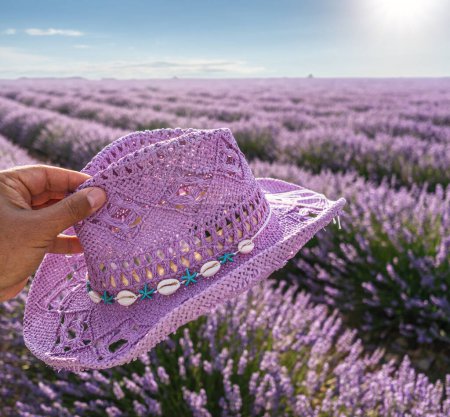 Photo for Violet sun hat in male hand  and lavender field stretching to the skyline. Brihuega, Spain. - Royalty Free Image