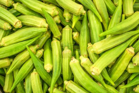 Téléchargez les photos : Des gousses de graines de gombo vertes sur le marché agricole. Contexte alimentaire. - en image libre de droit