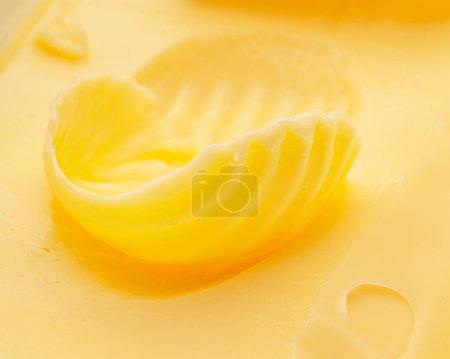 Foto de Rizos de mantequilla sobre el pedazo de la mantequilla de primer plano. Fondo alimentario. - Imagen libre de derechos