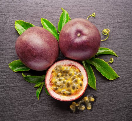 Photo for Dark purple passion fruits and half of maracuya fruit isolated on slate graphite gray background. - Royalty Free Image