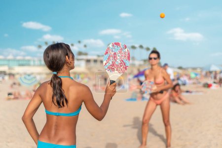 Téléchargez les photos : Maman et fille jouant au tennis de plage ou au padel tennis à la plage. - en image libre de droit