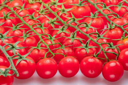 Foto de Lote de ramas de tomate rojo cereza cubiertas con pequeñas gotas de agua. Fondo alimentario. - Imagen libre de derechos