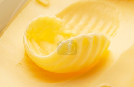 Foto de Rizos de mantequilla sobre el pedazo de la mantequilla de primer plano. Fondo alimentario. - Imagen libre de derechos
