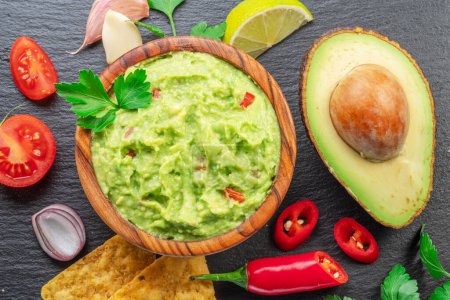 Photo for Guacamole sauce and  guacamole ingredients, popular Mexican food, on slate serving board. Top view. - Royalty Free Image