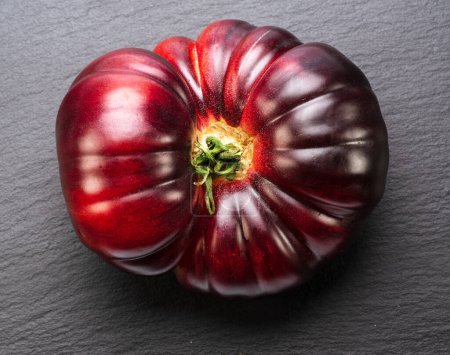 Téléchargez les photos : Tomate mûre noire ou violette sur fond de pierre d'ardoise grise. Vue du dessus. - en image libre de droit